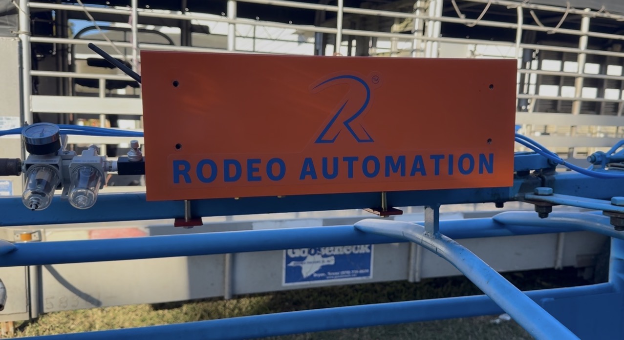 A ChuteTronix controller in an orange enclosure marked Rodeo Automation, mounted on a roping chute beside the air filter and regulator units that feed the gate cylinders.